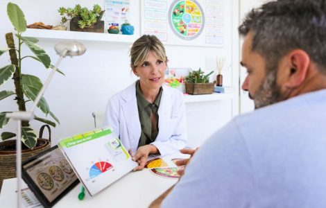 Argentinean nutritionist woman explaining her overweight man patient how to achieve a healthy and balanced diet with graphics, digit tablet and charts - Buenos Aires - Argentina